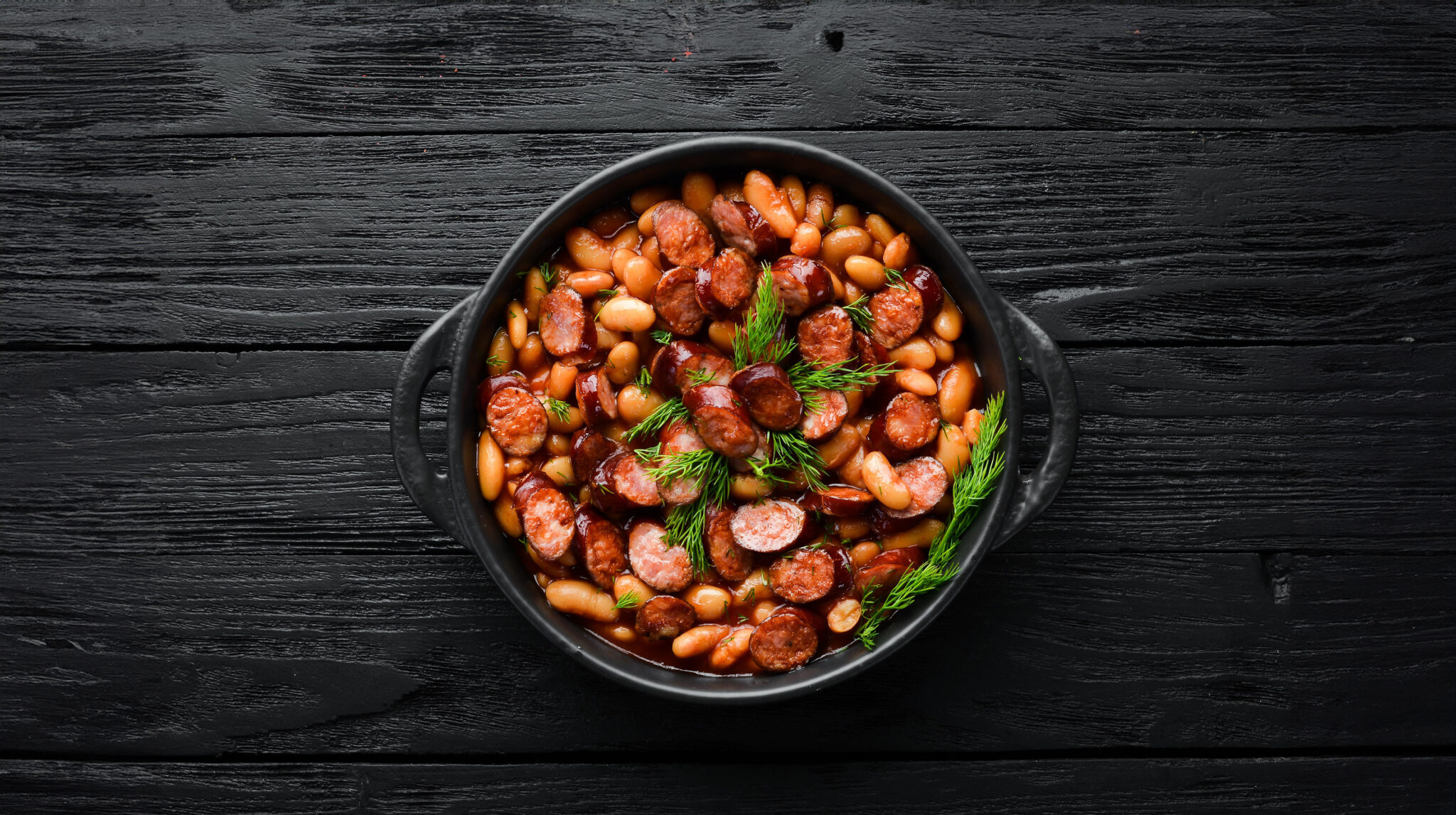 Beans,With,Sausages,In,Tomato,Sauce,On,A,Black,Plate.