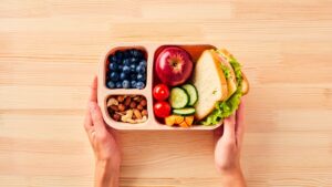 Women’s,Hands,Hold,Lunchbox,Of,Healthy,Food,Over,Wooden,Table.