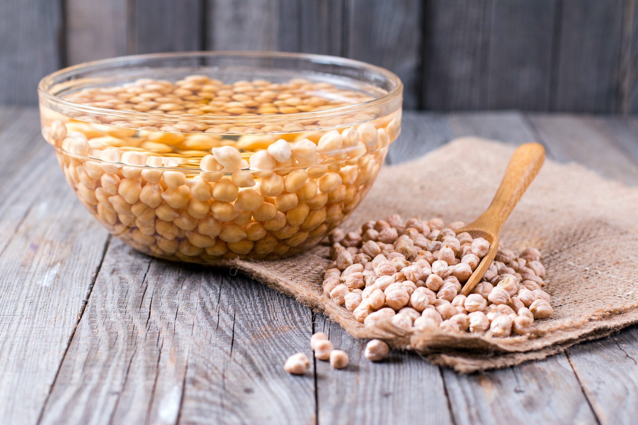 Uncooked,Chickpeas,In,Wooden,Spoon,On,Wooden,Background