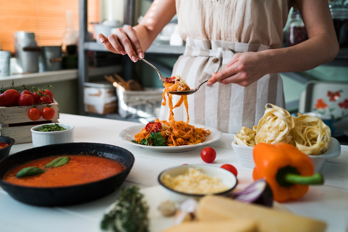 Young,Woman,In,Kitchen,Making,Delicious,Pasta,With,Sauce,Using