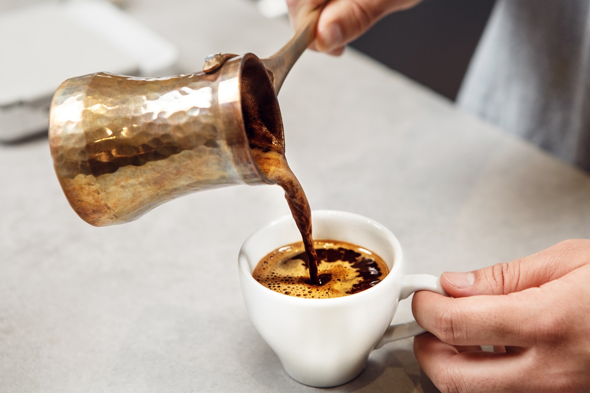 Traditional,Turkish,Coffee,Being,Poured,From,Copper,Cezve,Into,White