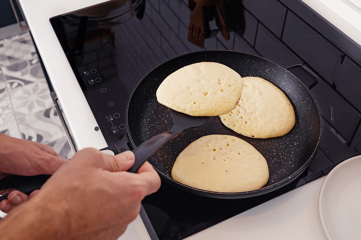 Man,Frying,Pancakes,On,The,Pan,At,His,Kitchen.,Preparing