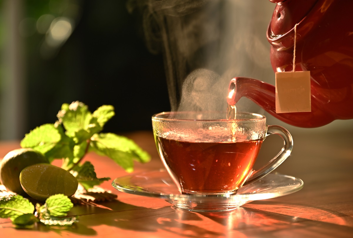 Hot,Tea,Pouring,From,Red,Pot,Into,Cup,In,Morning
