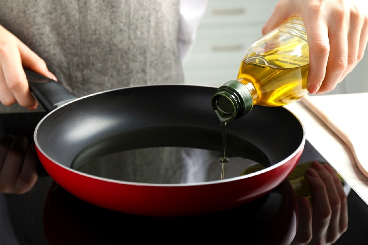 Woman,Pouring,Cooking,Oil,From,Bottle,Into,Frying,Pan,On