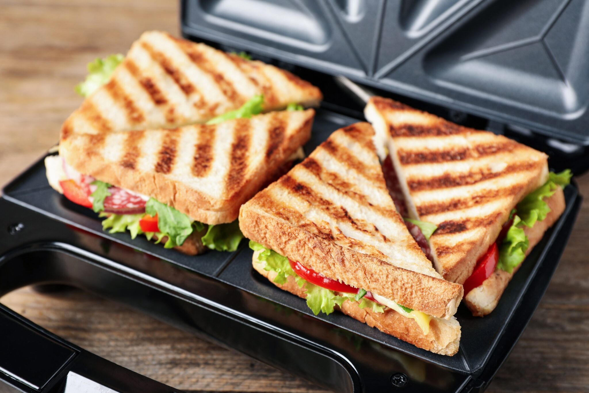 Modern,Grill,Maker,With,Sandwiches,On,Wooden,Table,,Closeup