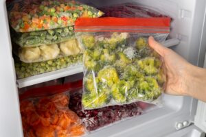 Female,Hands,Retrieving,Frozen,Broccoli,From,Freezer.,Plastic,Bags,With