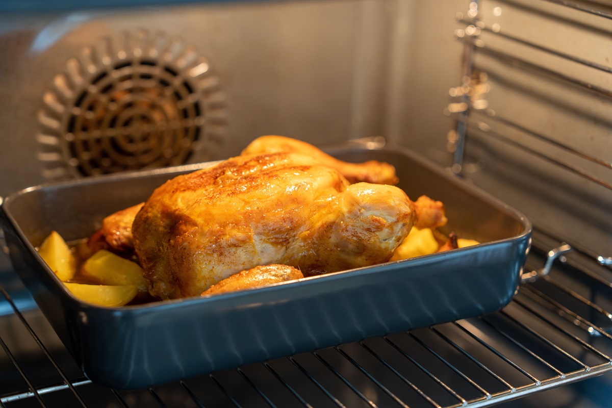 A,Roasting,Pan,Containing,A,Whole,Chicken,Inside,An,Oven