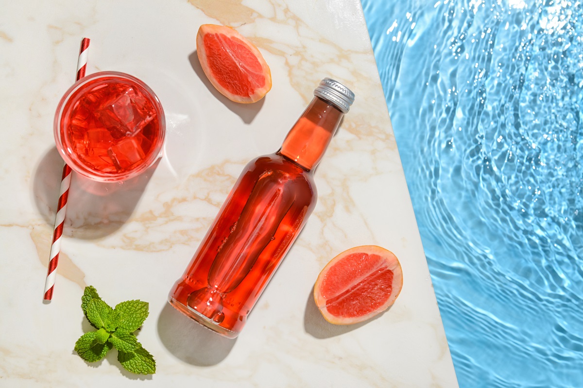 Bottle,Of,Fresh,Grapefruit,Soda,Near,Swimming,Pool