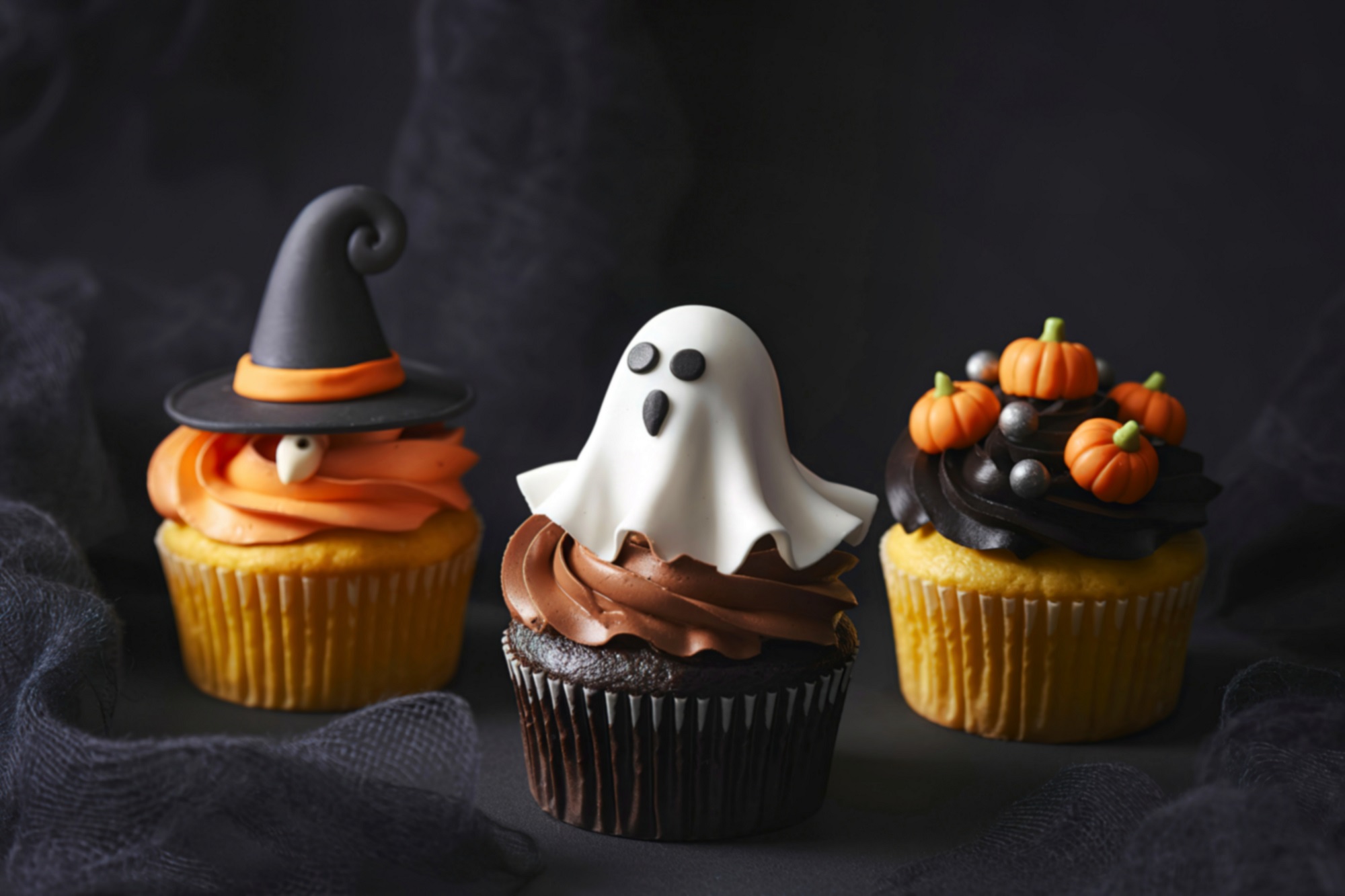 Three,Halloween,Themed,Cupcakes,Are,Displayed,Against,A,Dark,Background.